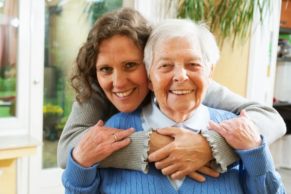 Younger woman with arms around elderly woman